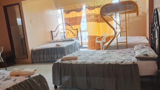 A dormitory room with two beds, a chair, a ladder, and an air conditioning unit. - Hotel Dorado (Guayaquil)