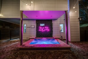 An outdoor pool area with a neon sign, surrounded by a wooden deck and a wall covered in foliage. - Modern DT Retreat w/ Hot Tub King Bed Fast Wi-Fi
 (Austin)