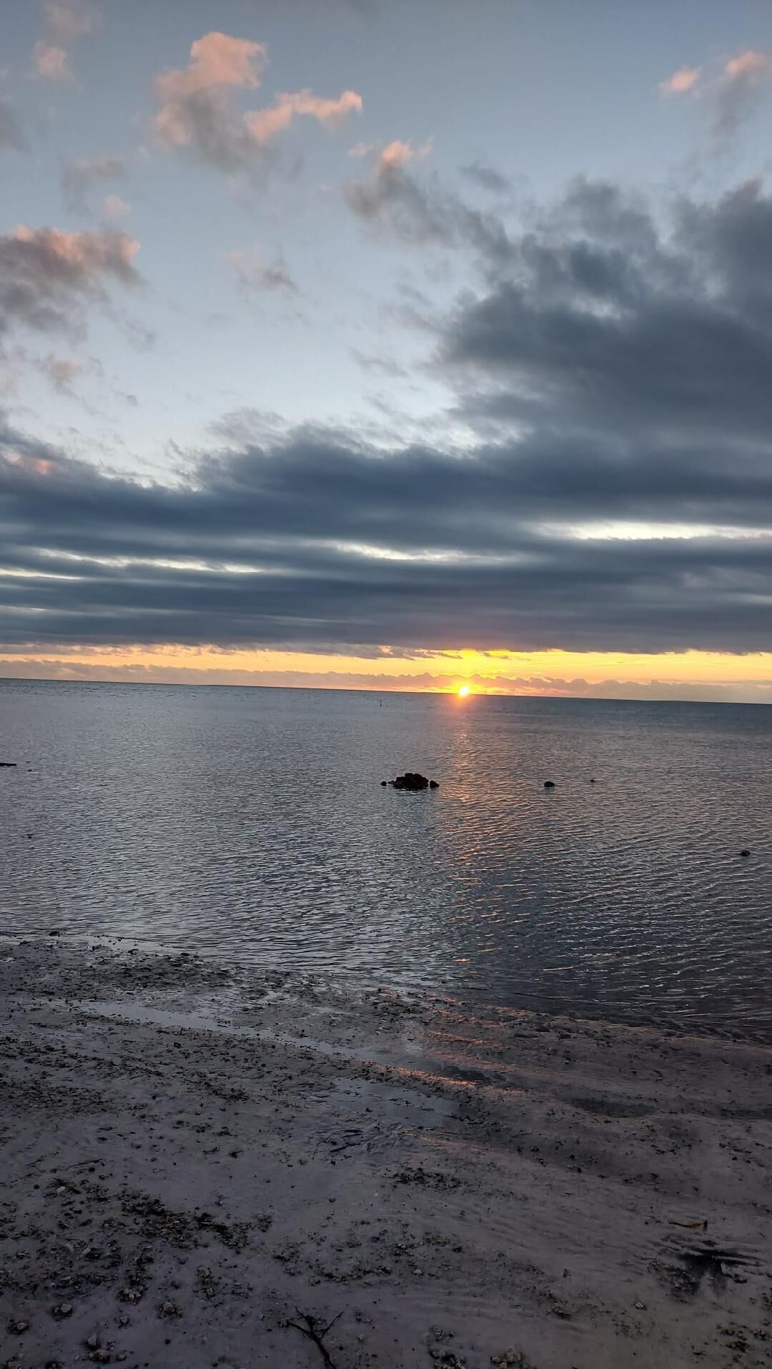 A beach with a sunset over the water.