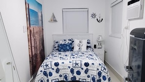 Ein Schlafzimmer mit einem Bett, einem Deckenventilator, einer Wandheizung und einem Fenster.