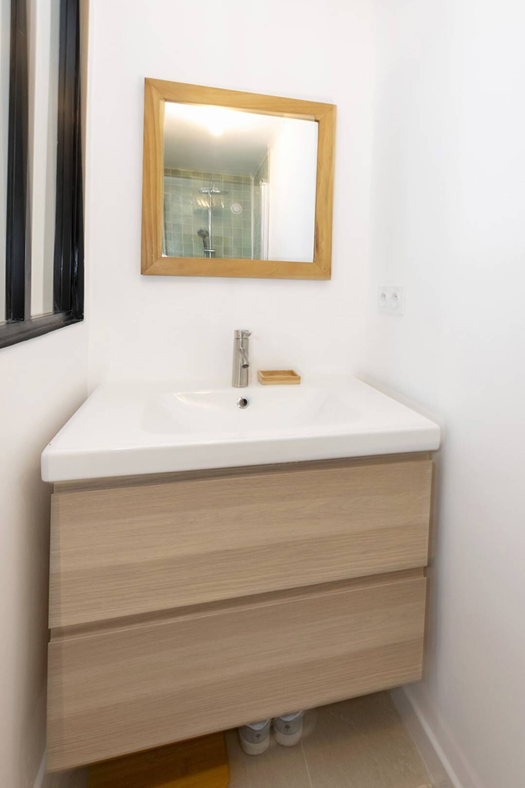 Ein Badezimmer mit einem weißen Waschbecken, einem Holzkosmetikschrank und einem Spiegel mit Holzrahmen.