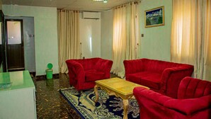 A room with a chandelier, red sofas, a wooden coffee table, and a patterned rug. - Zaytun Hotel Kano (Kano)