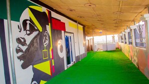 A corridor with green carpet, a mural on the wall, and a ceiling with circular lights. - Zaytun Hotel Kano (Kano)