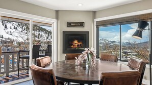 A dining area with a fireplace, a view of a snowy mountain, and a sign that reads "PARK CITY". - Walk to Main Street, Ontario Adventures, Two Homes Combined  - 6 BR, 2 Private Decks with Hot Tubs (Park City)
