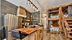 A modern kitchen with a wooden island, stainless steel appliances, and a loft bedroom with a wooden staircase.