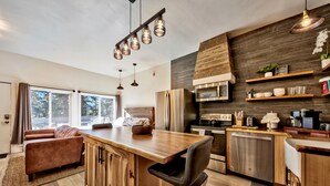 A modern kitchen with wooden cabinetry, stainless steel appliances, and a bar area.