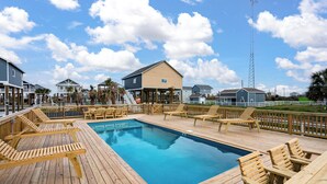 Eine Holzterrasse mit Pool, Liegestühlen und Blick auf Häuser.