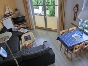 Ein Wohnzimmer mit einer Couch, einem Fernseher und einem Esstisch mit Stühlen.