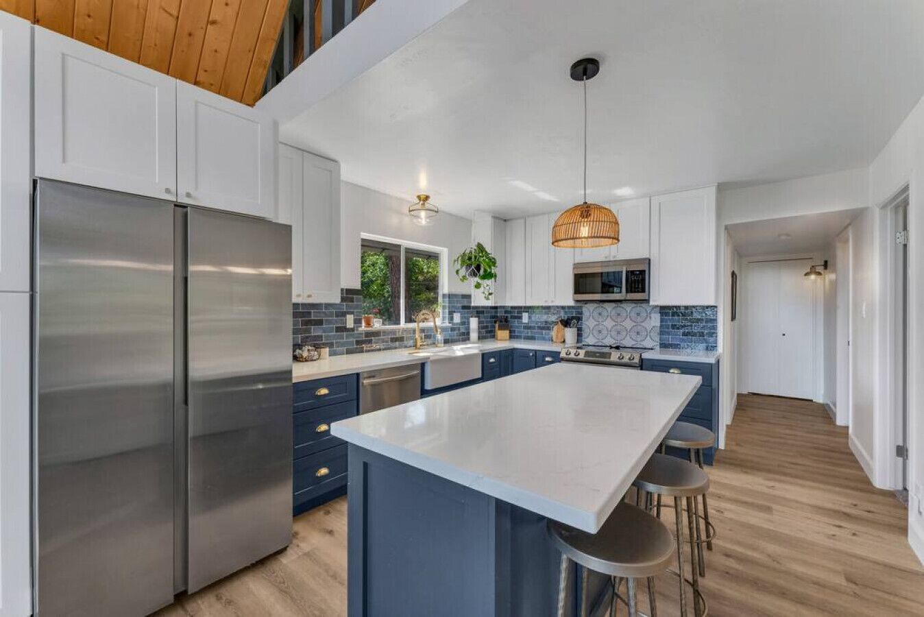 Una cocina moderna con una isla grande, electrodomésticos de acero inoxidable y una lámpara colgante.