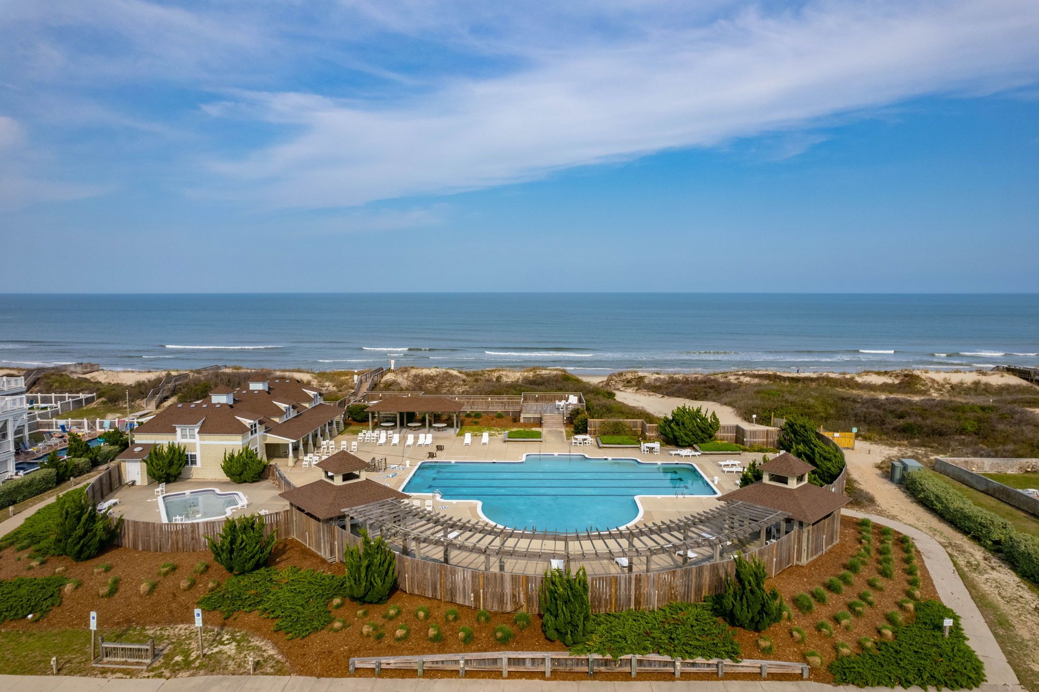 A resort with a large swimming pool, beachfront views, and a sandy beach area.