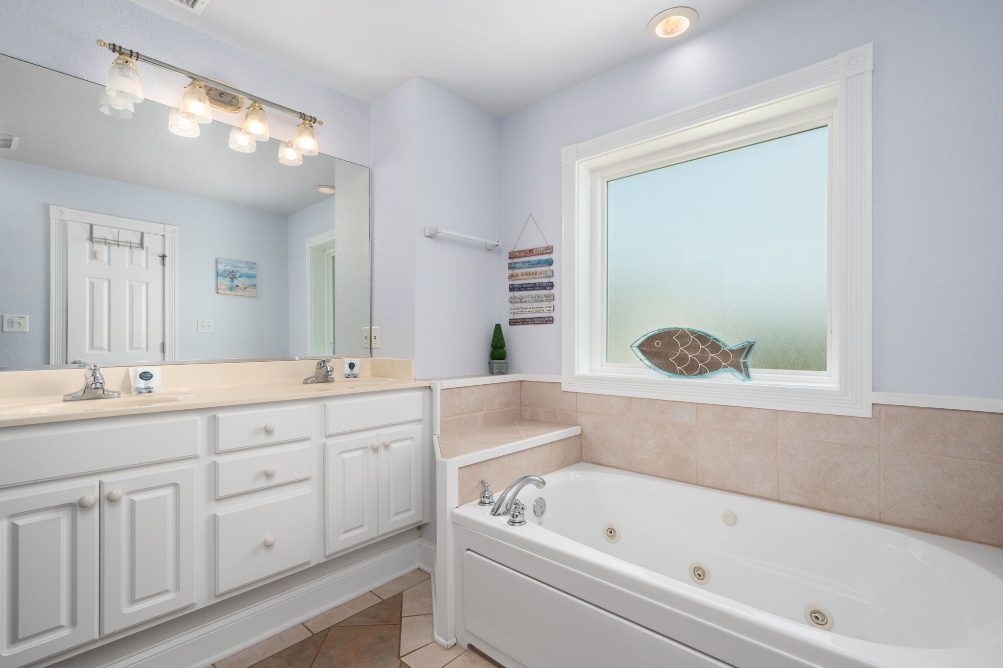 A bathroom with a large mirror, a bathtub, and a window with a view.