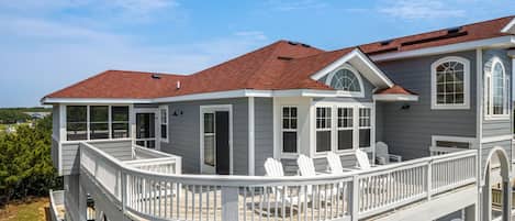 A two-story house with a covered deck and multiple windows.
