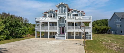 A large, two-story house with a balcony on each floor, a front entrance with steps, and a number "472" on the side.