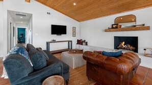 Un salon avec un plafond en bois, une cheminée, un téléviseur et un canapé.