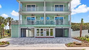 Un bâtiment à deux étages, avec une façade verte, un porche avant couvert et un garage.