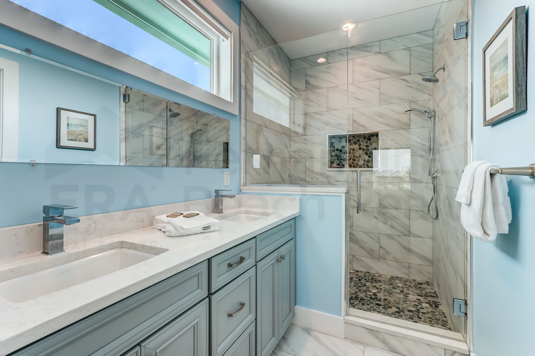A modern bathroom with a large sink, a shower, and a vanity with drawers.