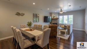 A spacious dining area with a large table and multiple chairs, a cozy seating area with a sofa and armchairs, and a fireplace. - New Build Walk-In 3BR Branson Condo w/ Patio + Indoor Pool | FH G-204 (Branson)