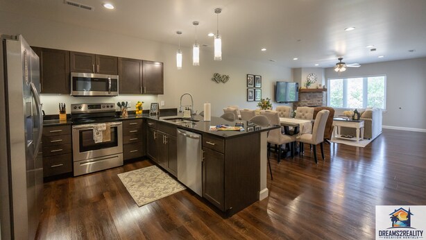 A modern kitchen with stainless steel appliances, a central island, and a dining area with a chandelier. - New Build Walk-In 3BR Branson Condo w/ Patio + Indoor Pool | FH G-204 (Branson)