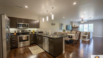 Una cocina moderna con electrodomésticos de acero inoxidable, una isla central y un comedor con candelabro.