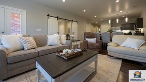 A spacious living room with a brown coffee table, a beige sofa, and a brown armchair. - New Build Walk-In 3BR Branson Condo w/ Patio + Indoor Pool | FH G-204 (Branson)