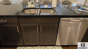 A kitchen with a stainless steel sink, dark cabinets, and a dishwasher. - New Build Walk-In 3BR Branson Condo w/ Patio + Indoor Pool | FH G-204 (Branson)