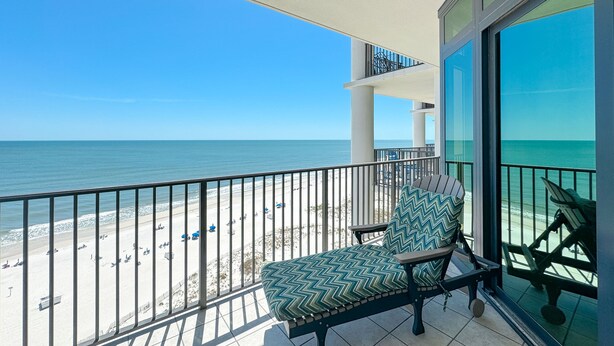 A balcony with a view of the beach and ocean.