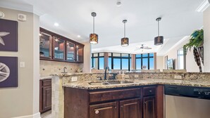 A modern kitchen with granite countertops, dark wood cabinets, and pendant lighting.