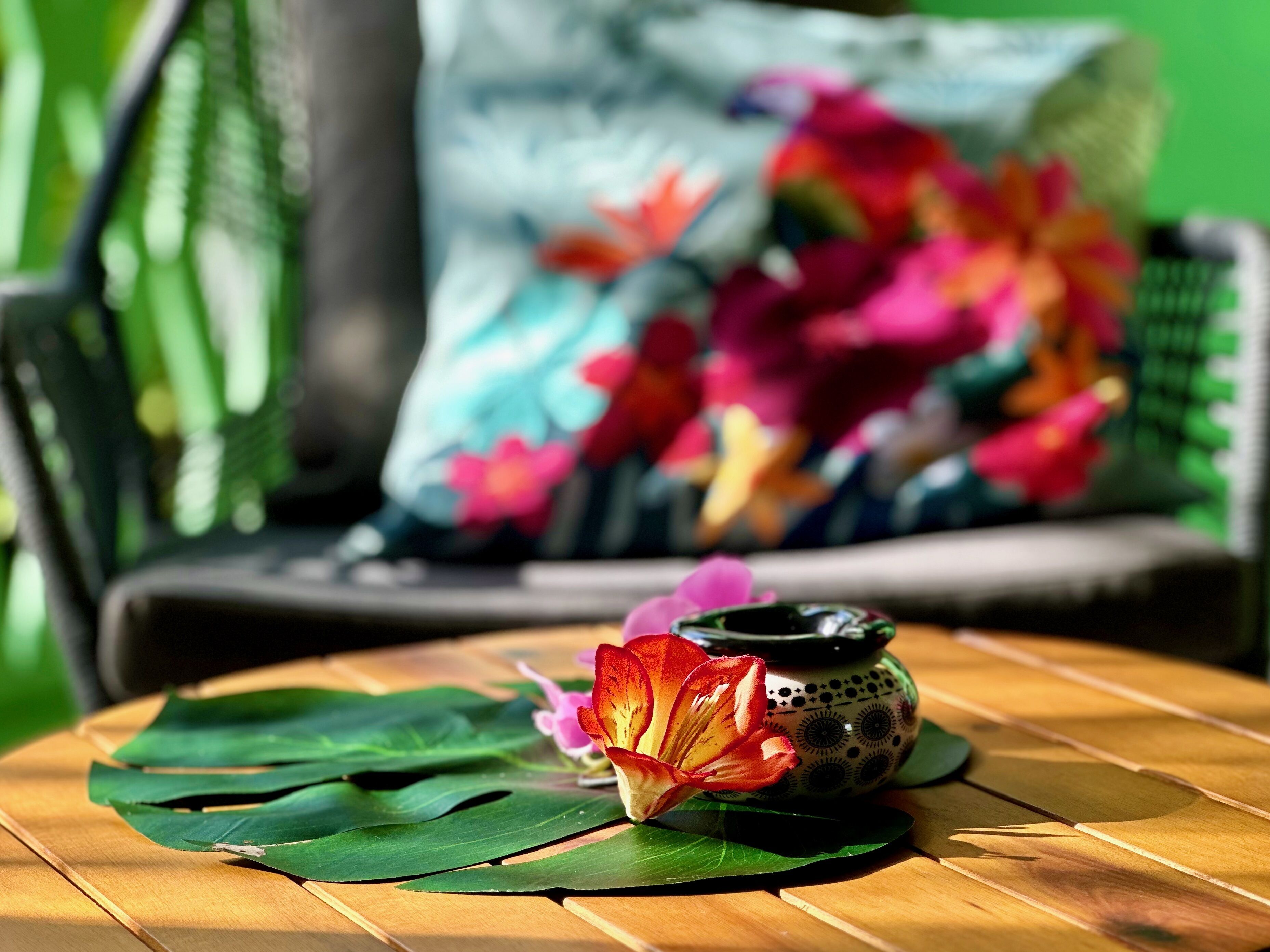 A wooden table with a decorative bowl and a flower on a green leaf.