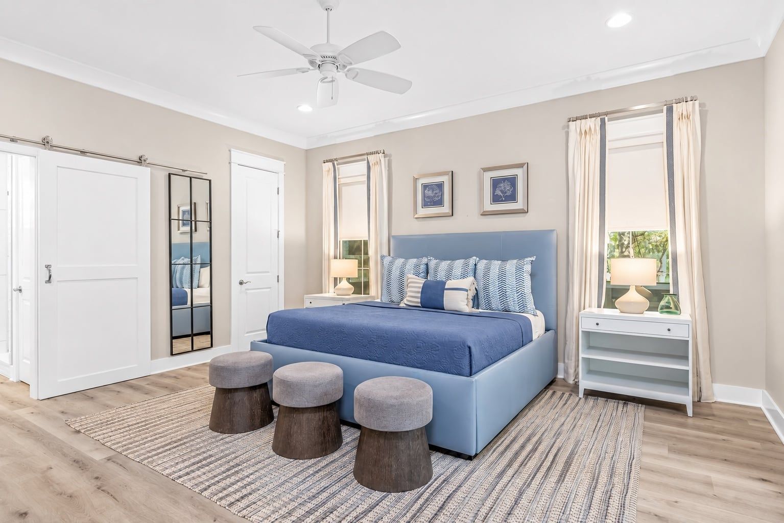 A bedroom with a bed, bedside tables, a ceiling fan, and a view of the outdoors.