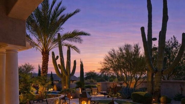 An outdoor patio with a table and chairs, surrounded by cacti and palm trees, under a clear sky. - Valley View Villa - Pool Heat Avail - Large Yard! (Scottsdale)