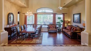 A spacious dining room with a large table and chairs, a sofa, and a chandelier. - Valley View Villa - Pool Heat Avail - Large Yard! (Scottsdale)