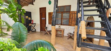Una habitación rústica con una escalera de madera, una pared de piedra y una puerta de madera.