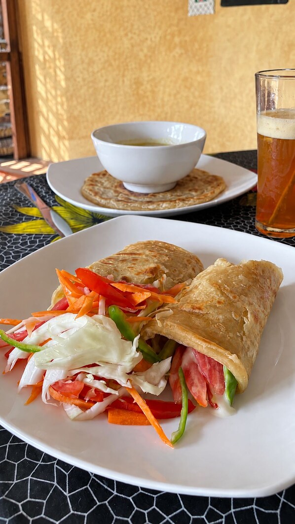 A meal consisting of a wrap with vegetables and a bowl of soup on a table.