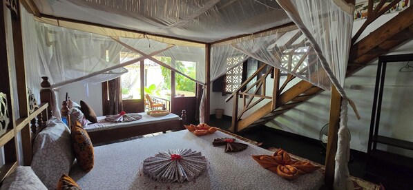 Um quarto com uma cama, um ventilador e uma escada.