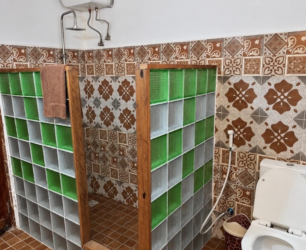Un baño con cabina de ducha, inodoro y azulejos decorativos en las paredes.