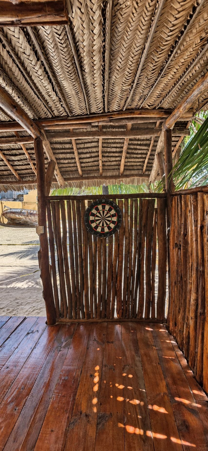 Una estructura de madera con techo de paja, un dardo y suelo de madera.