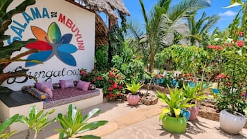 A garden area with a seating area, potted plants, and a sign with colorful flower graphics.
