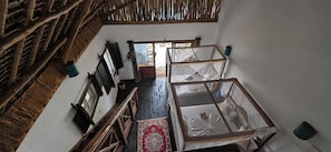 A room with a wooden staircase, a large window, and a bed with a mosquito net. - Salama & Mbuyuni Bungalows (Matemwe)