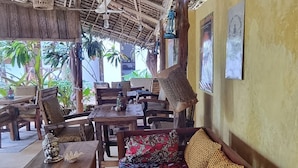 An indoor seating area with wooden furniture and a thatched roof. - Salama & Mbuyuni Bungalows (Matemwe)