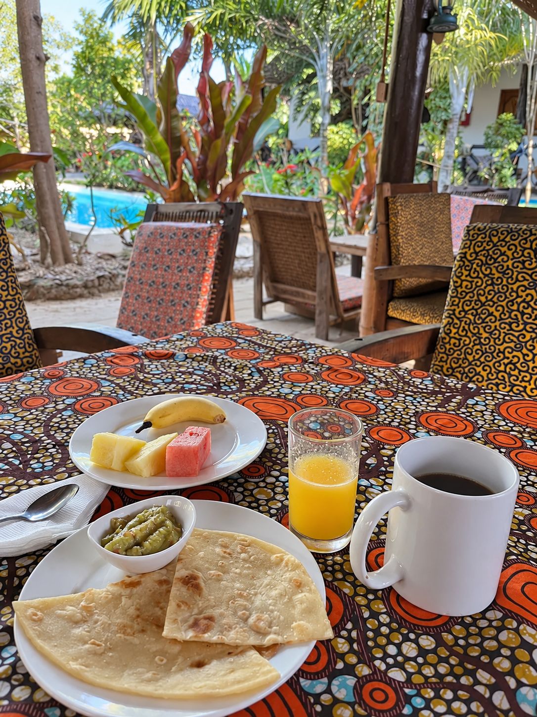 Un área de comedor al aire libre con una mesa dispuesta para el desayuno, que incluye un plato de comida, un vaso de jugo y una taza de café.