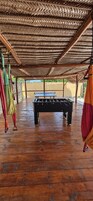 Un espacio interior con piso de madera, una mesa de futbolín y paraguas colgantes.