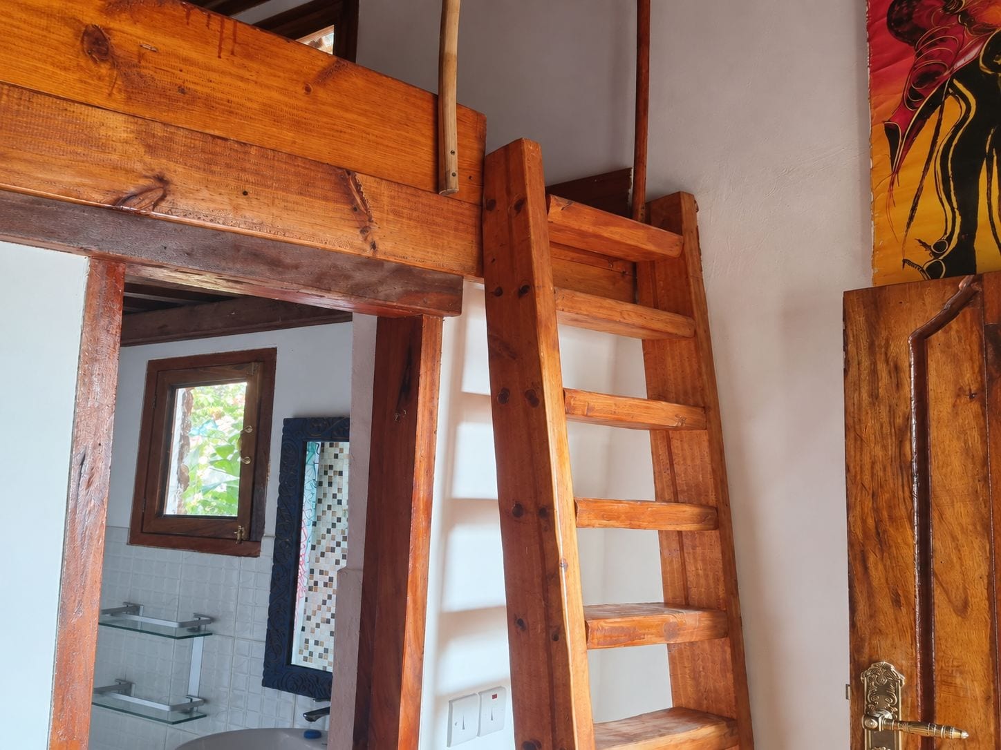 Une échelle en bois appuyée contre un mur dans une pièce dont le sol est carrelé et qui possède une fenêtre.