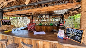 A rustic bar with wooden furniture and a thatched roof.