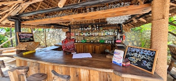 Un bar rústico con muebles de madera y techo de paja.