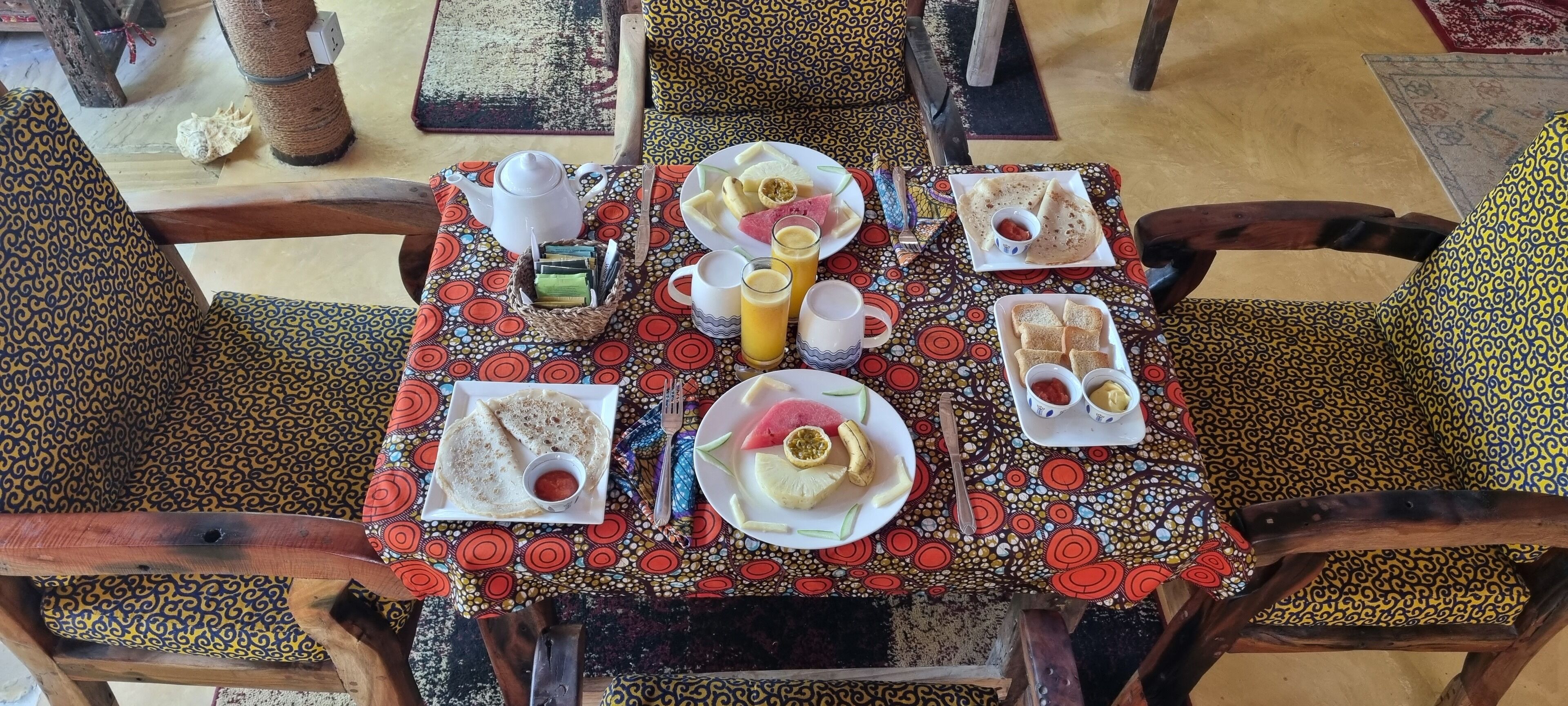 Una mesa puesta con platos de comida, una tetera y tazas.