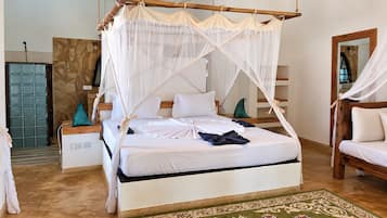 Una cama con dosel, un banco de madera y una alfombra estampada.
