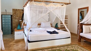 Una cama con dosel, un banco de madera y una alfombra estampada.