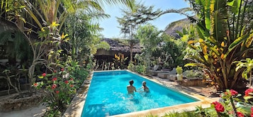 Una piscina rodeada de exuberante follaje y plantas tropicales.