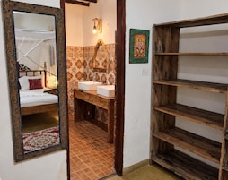Un baño con cama, lavamanos y espejo.