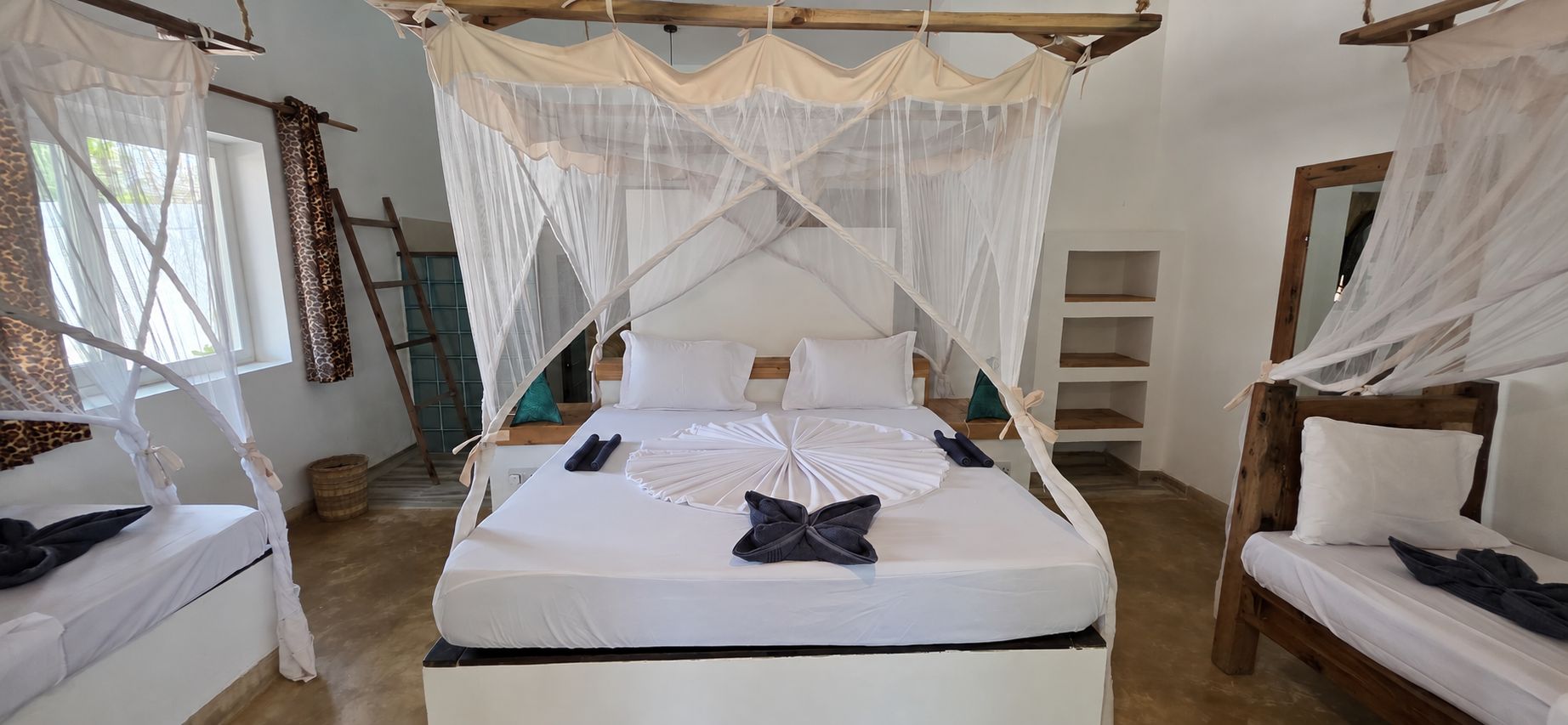 Una habitación con cama a dosel, un banco de madera y una mesita.